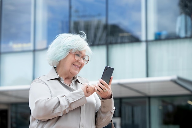 Ältere Geschäftsfrau, die draußen auf ihrem Handy tippt