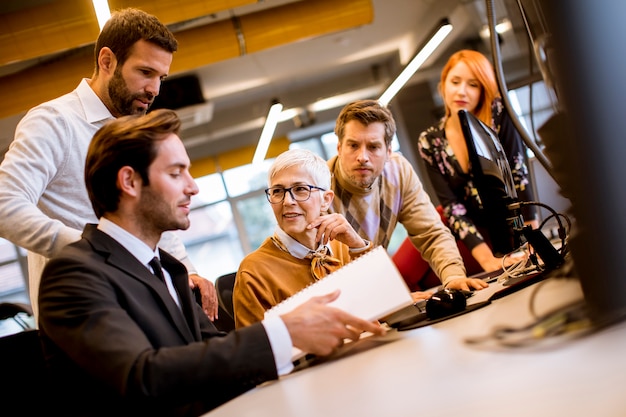 Ältere Geschäftsfrau, die zusammen mit jungen Geschäftsleuten im modernen Büro arbeitet