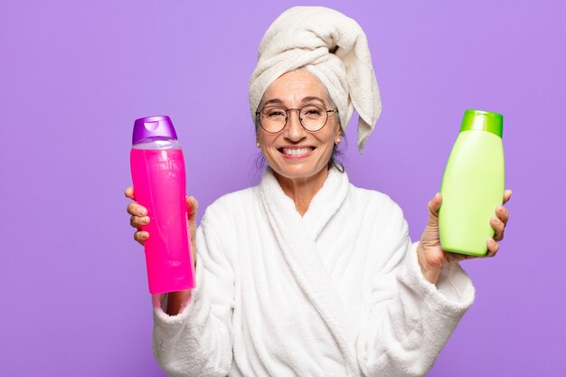 Ältere hübsche Frau nach dem tragenden Bademantel der Dusche. Gesichtsreinigungs- oder Duschproduktkonzept