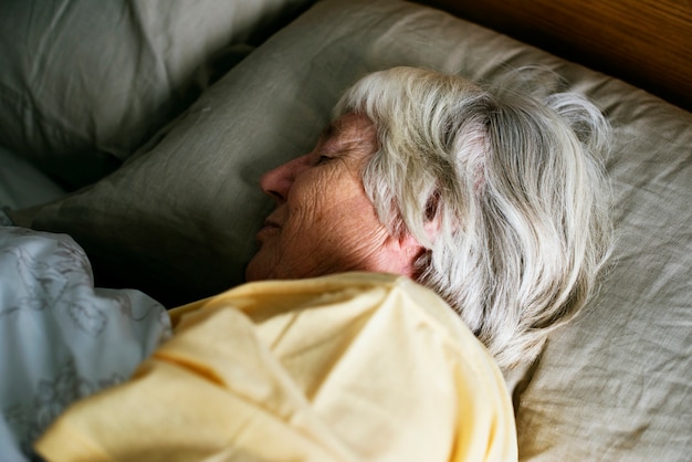 Ältere kaukasische Frau, die auf dem Bett schläft
