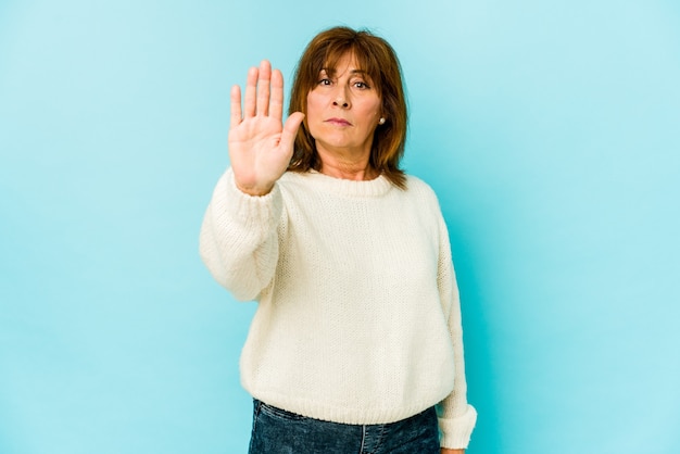 Ältere kaukasische Frau isoliert stehend mit ausgestreckter Hand, die Stoppschild zeigt, das Sie verhindert.