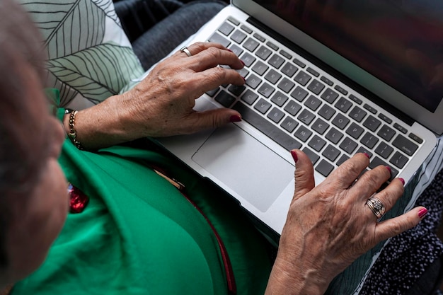 Ältere Latina-Frau arbeitet von zu Hause aus mit ihrem Laptop