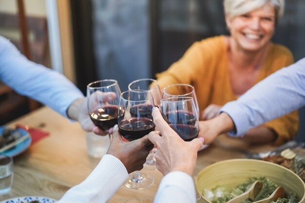 Ältere Leute, die Spaß haben, mit Wein beim Abendessen auf der Terrasse zu jubeln - Konzentrieren Sie sich auf das weibliche Gesicht