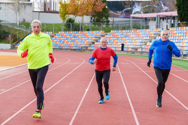 Ältere Männer laufen auf einer Outdoor-Leichtathletikbahn und führen einen gesunden und aktiven Lebensstil