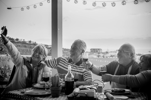 Ältere Menschen fotografieren mit dem Smartphone, während sie auf einem Tisch im Café gegen den Himmel Getränke trinken