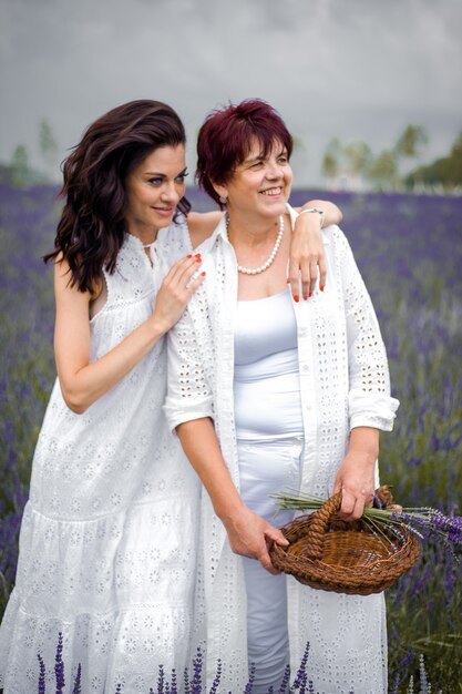 Ältere Mutter mit erwachsener Tochter, die auf das Lavendelfeld geht