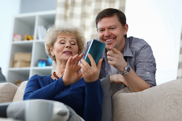 Ältere Mutter zeigt Foto im Telefon zum erwachsenen Sohn