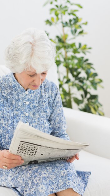 Ältere nette Frau, die Zeitungen liest
