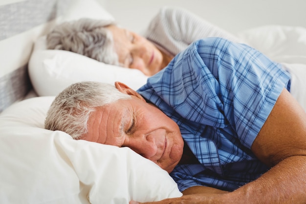 Ältere Paare, die auf Bett im Schlafzimmer schlafen