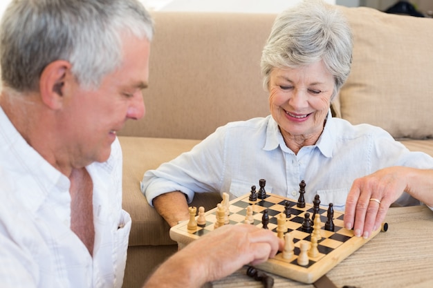 Ältere Paare, die auf dem Fußboden spielt Schach sitzen