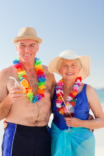 Ältere Paare, die ein Cocktail auf dem Strand trinken