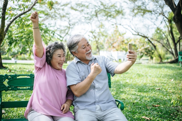 Ältere Paare, die ein selfie Foto mit intelligentem Telefon in einem Park machen