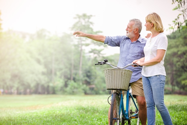 Ältere Paare, die ihr Fahrrad entlang glücklich glücklich sprechen gehen.