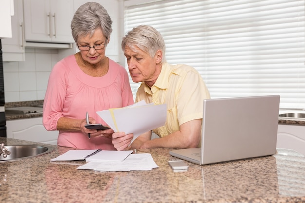 Ältere Paare, die ihre Rechnungen mit Laptop bezahlen