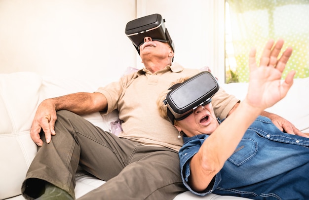 Ältere Paare, die Spaß zusammen mit Kopfhörer der virtuellen Realität haben
