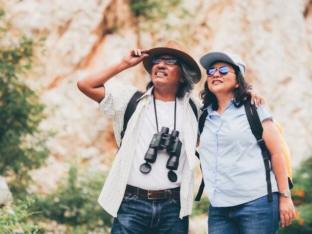 Ältere Paare reisen auf Sommerferien. Sie halten Händchen und wandern zusammen.