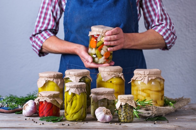 Ältere reife Frau, die in den Händen Glas mit hausgemachtem konserviertem und fermentiertem Essen hält. Auswahl an eingelegtem und mariniertem Gemüse. Hauswirtschaft, Hauswirtschaft, Ernteerhaltung