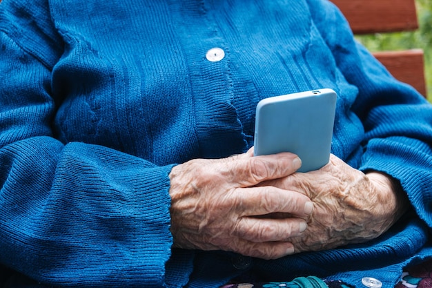 Ältere, reife Frau, Großmutter, die ein Handy hält und Apps für Mobilgeräte benutzt und auf den Bildschirm schaut