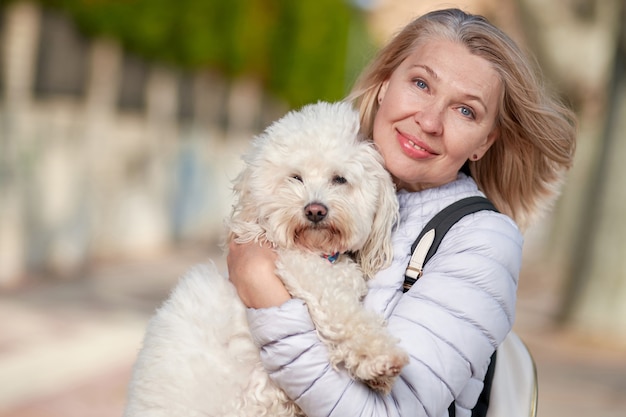 Ältere Rentnerfrau gehen Park weißen kleinen Hund.