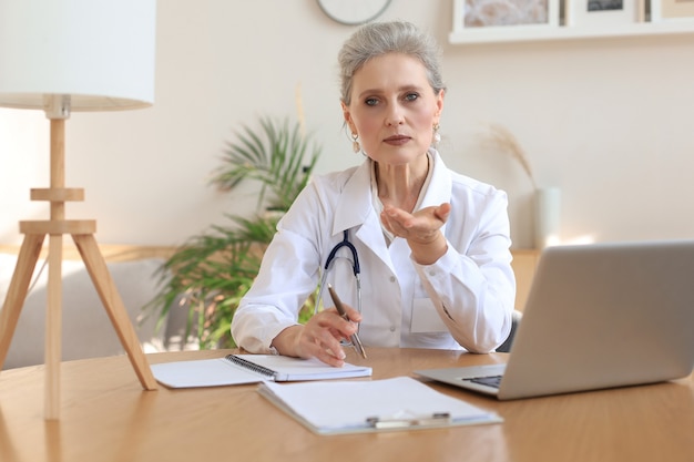 Ältere Ärztin Therapeutin mit Headset-Videoanruf im Gespräch mit der Webkamera, die den virtuellen Patienten online per Videokonferenz-Chat berät.