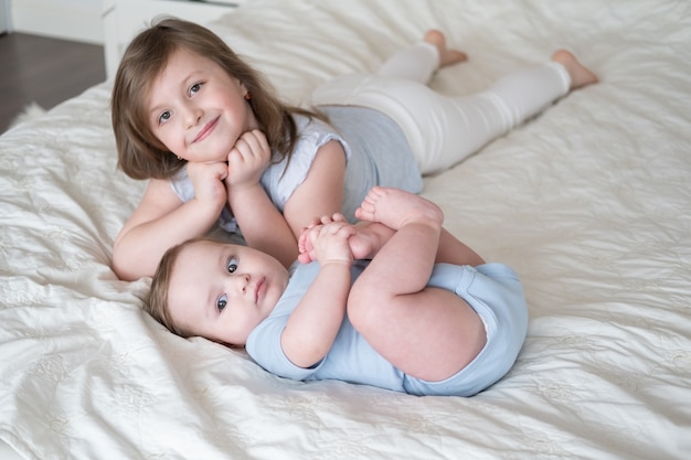 Ältere Schwester des Mädchens, die mit ihrem kleinen kleinen Bruder zu Hause auf dem Bett liegt