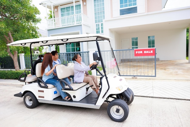 Ältere Verkaufsagentur, die einen Golfwagen fährt, präsentiert der Familie ein neues Haus, um Immobilien zu verkaufen