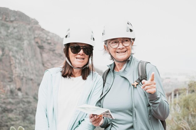 Ältere Wandererinnen mit Helmen, die auf der Spitze von Bergsteigertouristen stehen, die Ferien genießen