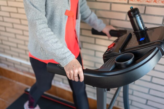 Ältere weiße Frau, die auf einem Laufband Sport treibt, um zu Hause zu gehen und in Form zu bleiben