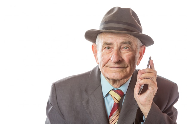 Älterer älterer alter Mann mit einem Retro-Hut, der auf Handy lokalisiert auf weißem Hintergrund spricht.