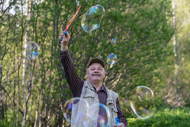 Älterer aktiver Mann spielt mit Seifenblasen im Freien