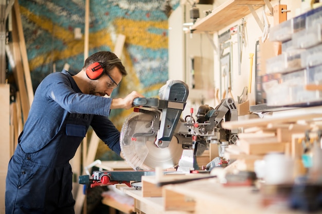 Älterer Arbeiter, der Holz schneidet