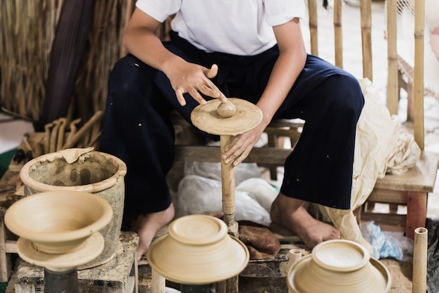 Älterer asiatischer handcraft Töpfer, der eigenhändig Tongefäßerdwaren herstellt.