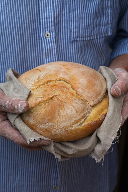 Älterer Bäcker mittleren Alters, der frisch gebackenes Brot in seinen Händen hält