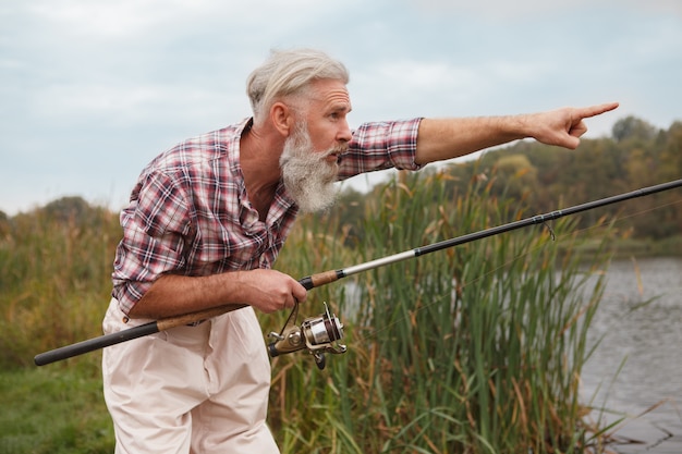 Älterer bärtiger Mann, der auf einem See fischt