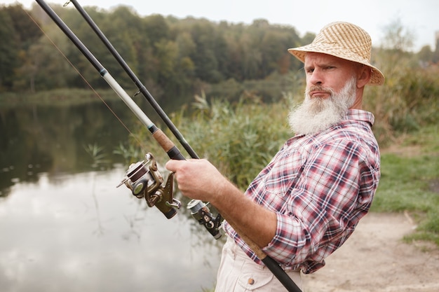 Älterer bärtiger Mann, der auf einem See fischt