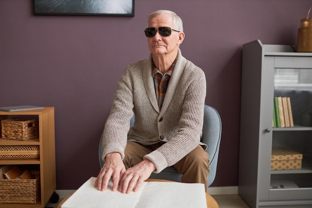 Älterer blinder Mann mit Brille, der ein Buch liest