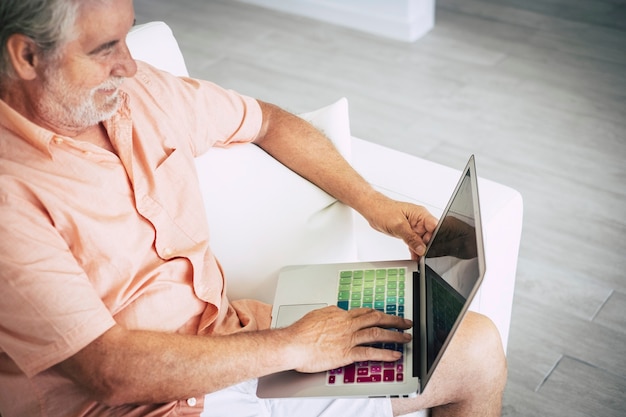 Älterer erwachsener weißer Haar im Alter von kaukasischen Mann von oben mit einem farbigen Laptop gesehen, um im Web zu suchen?