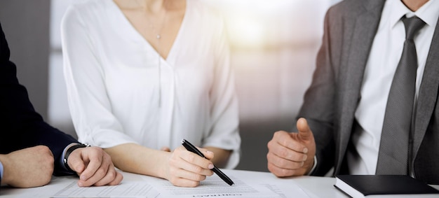 Älterer Geschäftsmann und eine Gruppe von Geschäftsleuten diskutieren Verträge im sonnigen Büro, Nahaufnahme.