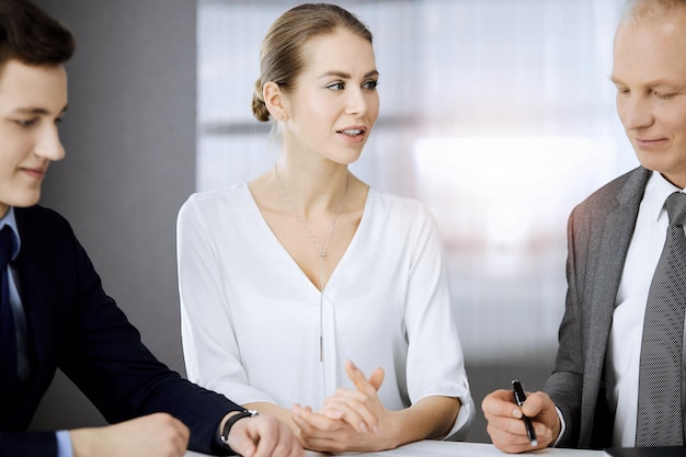 Älterer Geschäftsmann und eine Gruppe von Geschäftsleuten diskutieren Verträge im sonnigen Büro. Teamarbeit und Zusammenarbeit.