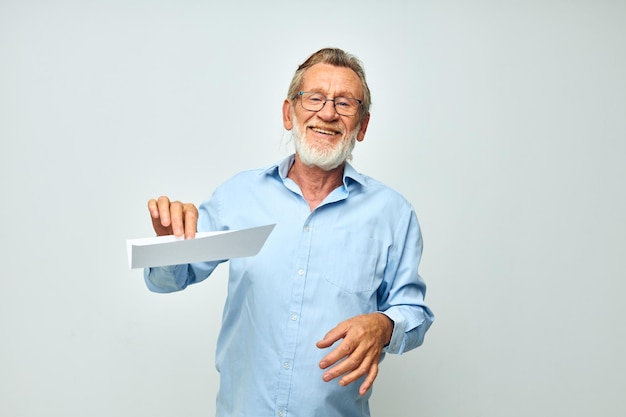 Älterer grauhaariger Mann, der ein Blatt Papier hält, das einen isolierten Hintergrund darstellt