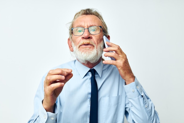 Älterer grauhaariger Mann in einem Hemd mit Krawatte, der am Telefon telefoniert, beschnittene Ansicht