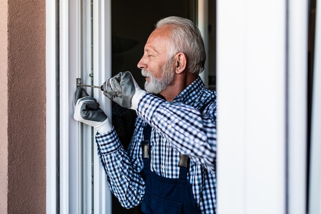 Älterer Heimwerker, der Fenster repariert. Renovierung.