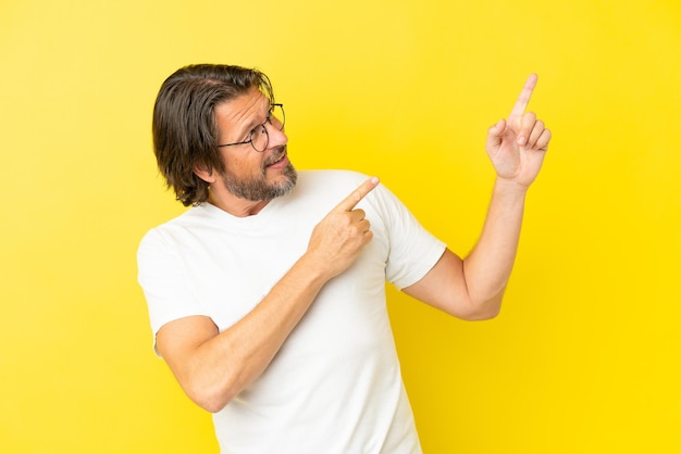 Älterer holländischer Mann isoliert auf gelbem Hintergrund, der mit dem Zeigefinger eine großartige Idee zeigt