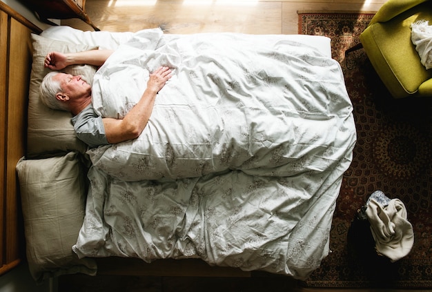 Älterer kaukasischer Mann, der auf dem Bett schläft