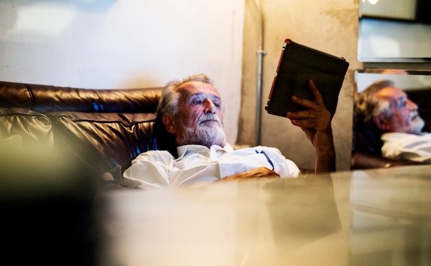 Älterer kaukasischer Mann, der digitale Tablette verwendet