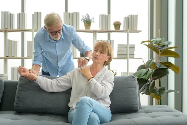 Älterer kaukasischer Mann, der Massage für seine Frau im Wohnzimmer tut