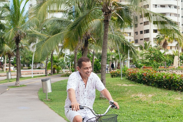 Älterer Latino-Mann, der im Park Fahrrad fährt