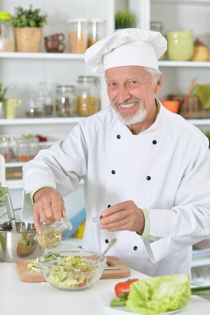 Älterer männlicher Koch, der Abendessen in der Küche zubereitet