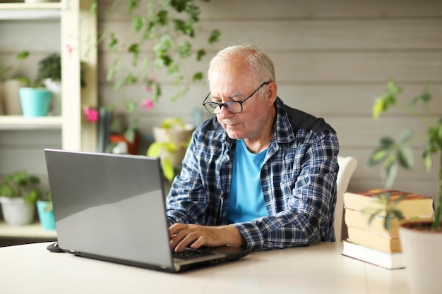 Älterer Mann, der am Computer arbeitet, während er zu Hause sitzt