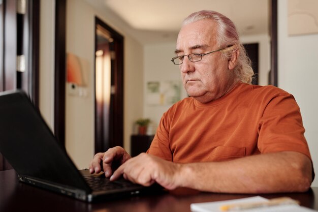 Älterer Mann, der am Laptop arbeitet